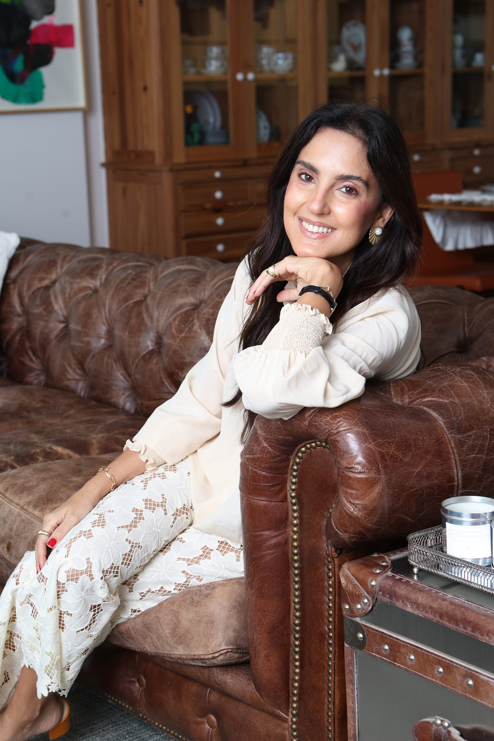 Ana Luisa do Rego Macedo sorrindo, sentada em um sofá de couro